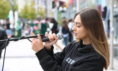 独立民谣歌曲新人歌手封面，街头演出场景配温暖自然光线